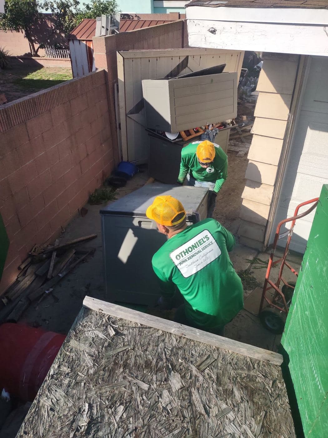 Othoniel's Junk Removal crew hauling out an old cabinet and appliances